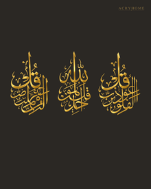 Three-panel Qul set in mirror gold acrylic, vertical Arabic calligraphy catching warm light above a console table.