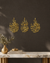 Three-panel Qul set in mirror gold acrylic, vertical Arabic calligraphy catching warm light above a console table.