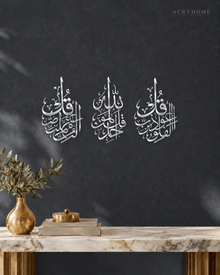Three vertical acrylic panels in mirror silver, each with one short surah in Arabic calligraphy, hung together as a set.