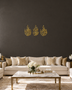 Three-panel Qul set in mirror gold acrylic, vertical Arabic calligraphy catching warm light above a console table.