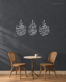 Three vertical acrylic panels in mirror silver, each with one short surah in Arabic calligraphy, hung together as a set.
