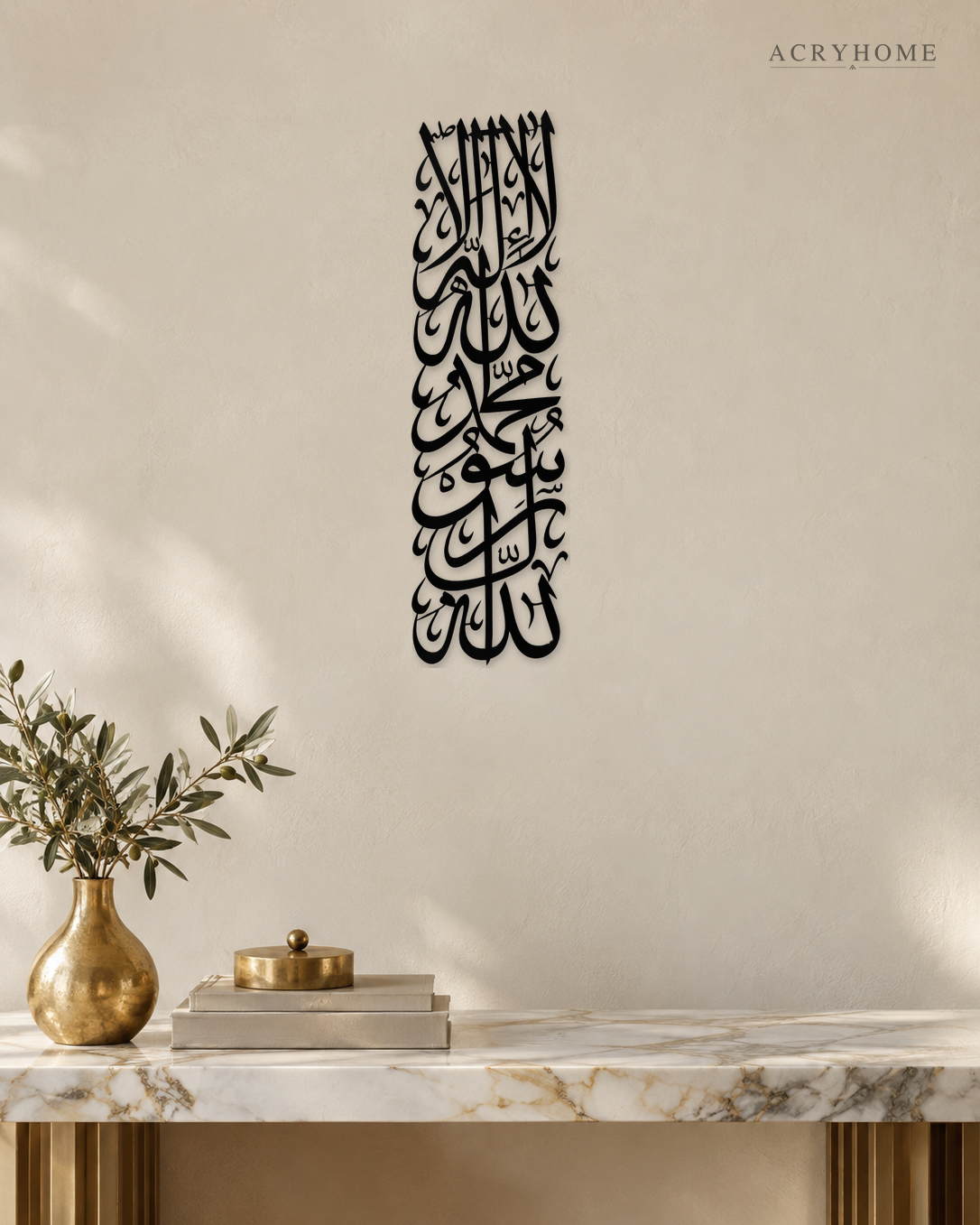Tall vertical Kalima calligraphy in gloss piano black acrylic, stacked Thuluth lines float-mounted on a pale plaster wall above a console table