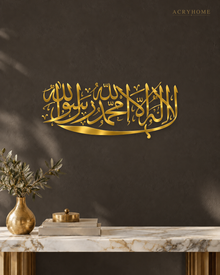 Kalima calligraphy in mirror gold acrylic, one sweeping horizontal line of Thuluth, float-mounted above a marble console