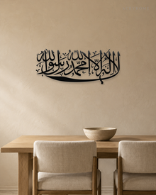 Kalima calligraphy in gloss piano black acrylic, one sweeping horizontal line of Thuluth, float-mounted above a marble console
