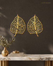 Pair of mirror gold acrylic leaf-shaped wall panels with open vein detail and Arabic calligraphy centred in each leaf