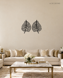 Set of two gloss black acrylic leaf panels with fine vein lattice and Arabic calligraphy at the centre of each, float-mounted on a pale wall