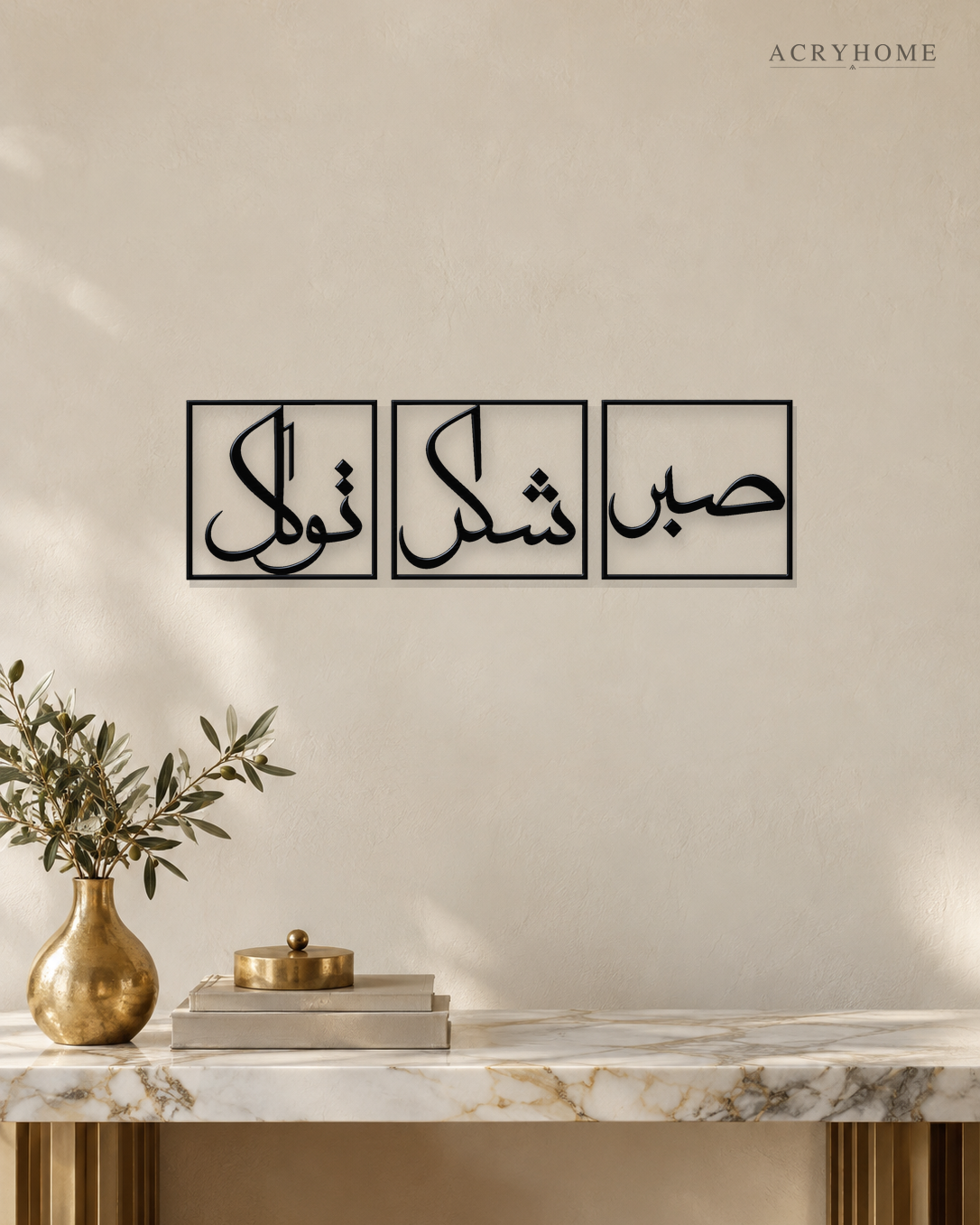 Set of three gloss black acrylic panels reading Sabr, Shukr and Tawakkul in Arabic, each inside a slim rectangular border, hung in a row on a pale ivory wall