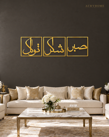 Set of three mirror gold acrylic panels reading Sabr, Shukr and Tawakkul in Arabic, each inside a slim rectangular border, hung in a row on a warm espresso wall