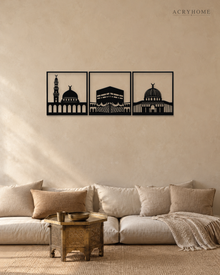 Set of three gloss black acrylic wall panels showing the silhouettes of Al-Masjid al-Haram, Al-Masjid an-Nabawi and Al-Aqsa, hung in a row on a pale wall.