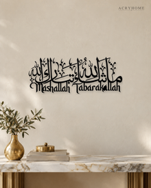 Mashallah Tabarakallah acrylic wall art in gloss piano black, Arabic calligraphy above English script, float-mounted on a pale wall