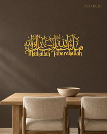 Mashallah Tabarakallah acrylic wall art in mirror gold, Arabic calligraphy above English script, float-mounted on a dark wall