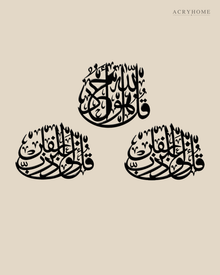 Three Quls Arabic calligraphy wall art in gloss black acrylic, one cluster above and two below, float-mounted on a pale wall.