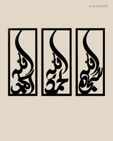 Set of three narrow vertical acrylic wall panels in gloss piano black, each framing a single Arabic word in tall flowing calligraphy, float-mounted in a row on a pale wall.