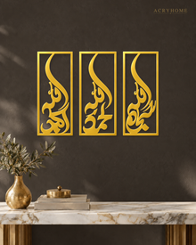 Set of three narrow vertical acrylic wall panels in mirror gold, each framing a single Arabic word in tall flowing calligraphy, float-mounted in a row on a pale wall.
