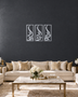 Set of three narrow vertical acrylic wall panels in mirror chrome silver, each framing a single Arabic word in tall flowing calligraphy, float-mounted in a row on a pale wall.