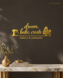 Bakery & Patisserie Wall Sign with Mixer and Cake in mirror gold acrylic, float-mounted on a deep charcoal wall.