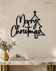 Merry Christmas Script Wall Sign with Outline Tree in gloss piano black acrylic, float-mounted on a pale ivory wall.