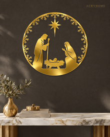 Round Nativity scene wall art in mirror gold acrylic — Mary, Joseph and the manger beneath the star, ringed by a pine and snowflake wreath, float-mounted on a pale wall.