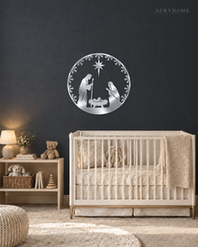 Round Nativity scene wall art in mirror silver acrylic — Mary, Joseph and the manger beneath the star, ringed by a pine and snowflake wreath, float-mounted on a pale wall.