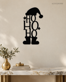 Ho Ho Ho Christmas Wall Art with Hat and Boots in gloss piano black acrylic, float-mounted on a pale ivory wall.