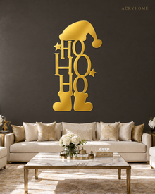Ho Ho Ho Christmas Wall Art with Hat and Boots in mirror gold acrylic, float-mounted on a deep charcoal wall.
