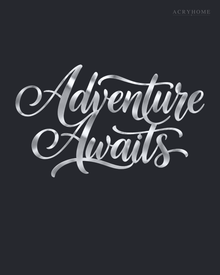 Adventure Awaits brush script wall art in mirror silver acrylic, float-mounted on a light wall above a desk