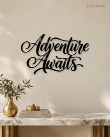 Adventure Awaits brush script wall art in gloss piano black acrylic, float-mounted above a console table on a pale plaster wall