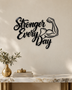 Stronger Every Day script wall art with flexed-arm icon in gloss piano black acrylic, float-mounted above a home gym bench.