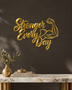 Stronger Every Day script wall art with flexed-arm icon in mirror gold acrylic, catching light on a pale gym wall.