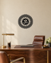 Gloss black acrylic Om sunburst mandala wall art, float-mounted on a pale wall with layered petal and diamond rings around the central Om symbol