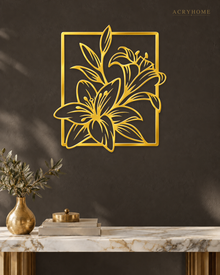 Lily line art wall piece in mirror gold acrylic, fine stems and leaves breaking past a slim rectangular frame, float-mounted above a console.