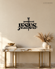 JESUS wall art in gloss piano black acrylic, heavy block letters with a cross and nails set into the lettering and a banner beneath reading The Way, The Truth, The Life, float-mounted on a pale wall