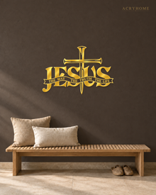 JESUS wall art in mirror gold acrylic, heavy block letters with a cross and nails set into the lettering and a banner beneath reading The Way, The Truth, The Life, float-mounted on a pale wall