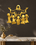 Silhouette of Jesus with arms outstretched above kneeling children, laser-cut in mirror gold acrylic and float-mounted on a pale wall.