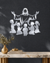Silhouette of Jesus with arms outstretched above kneeling children, laser-cut in mirror silver acrylic and float-mounted on a pale wall.