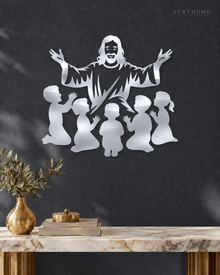Silhouette of Jesus with arms outstretched above kneeling children, laser-cut in mirror silver acrylic and float-mounted on a pale wall.