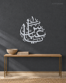 Arabic name calligraphy in mirror silver acrylic, float-mounted so the flowing strokes cast a soft shadow.