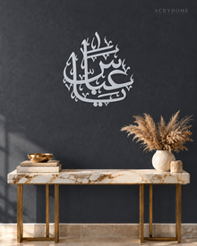 Arabic name calligraphy in mirror silver acrylic, float-mounted so the flowing strokes cast a soft shadow.