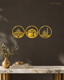 Three Holy Mosques Roundels — Acrylic Islamic Wall Art in mirror gold acrylic, float-mounted on a deep charcoal wall