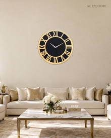 Gold and black Roman numeral wall clock hung above a sofa in a living room.