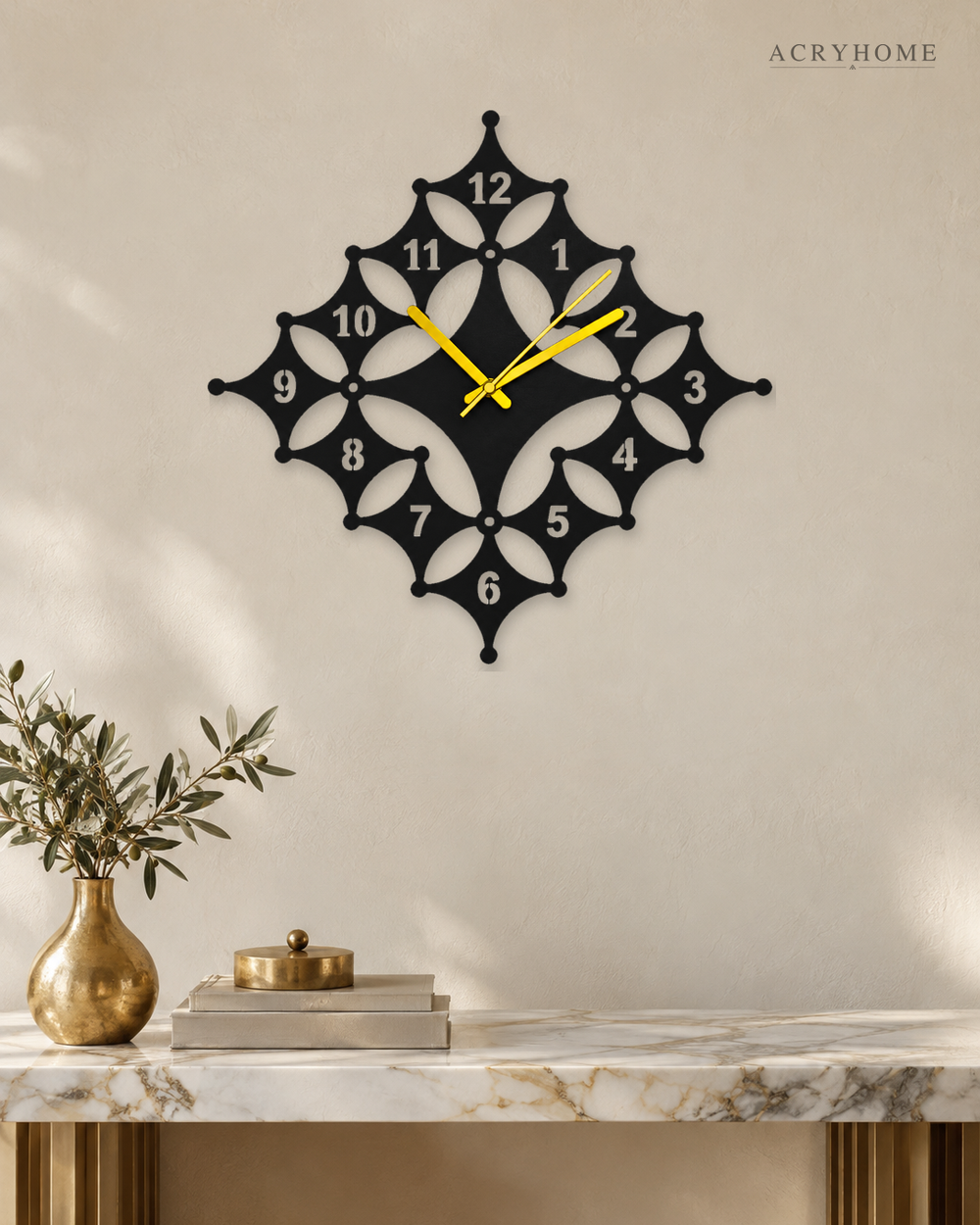 Floral diamond wall clock in black and white acrylic, square set on the diagonal, on a pale wall.