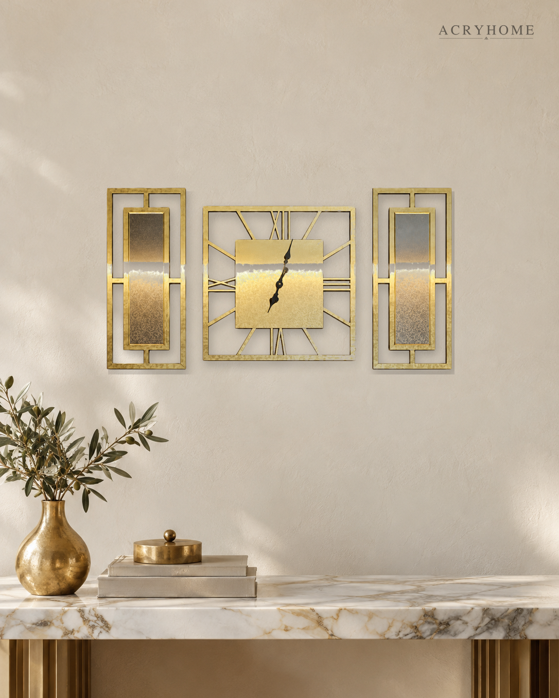 Gold mirror clock and panel set of three, a square clock between two framed panels, on a pale wall.
