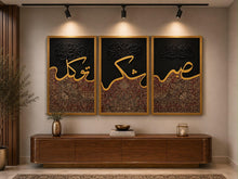 Three-panel Arabic calligraphy set reading Sabr, Shukr and Tawakkul in gold over a burgundy Persian weave, in gold frames above a walnut console